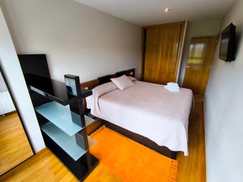 a small bedroom with a bed and a shelf at Piso en primera linea de Playa en Laxe in Laxe