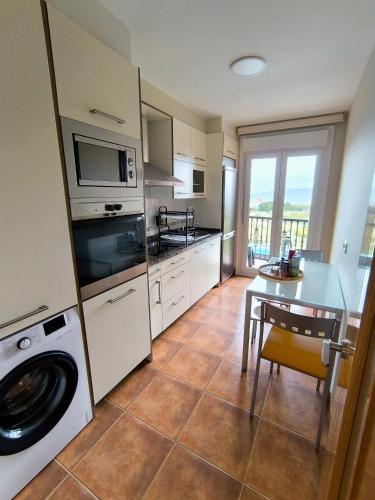 a kitchen with a washer and dryer and a table at Piso en primera linea de Playa en Laxe in Laxe