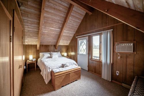 una camera da letto con un letto in una stanza con pareti in legno di Rustic Cabin Rental with a Hot Tub near Windham, New York a Windham