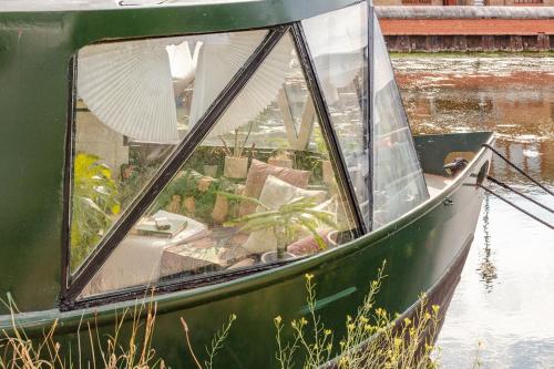 a green boat is sitting in the water at The Floating Terrarium in London