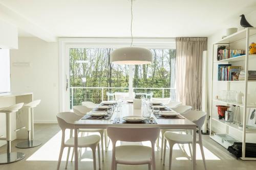 a white dining room with a table and chairs at Zeesamen 5 min from beach in Cadzand