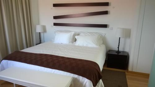 a bedroom with a large bed with white sheets and pillows at Casas de Campo da Barroca in Tabosa