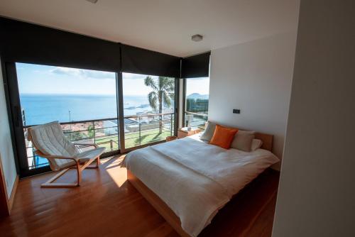 a bedroom with a bed and a chair and the ocean at Villa Cary in Funchal