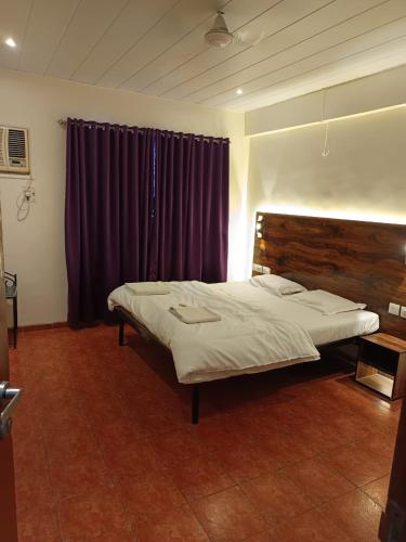 ein Schlafzimmer mit einem großen Bett und lila Vorhängen in der Unterkunft Hotel Aramdham in Jāmb