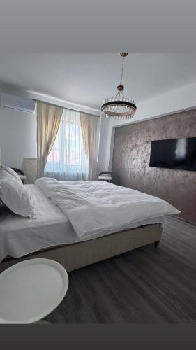 a bedroom with a large white bed and a table at David Apartament in Buzău