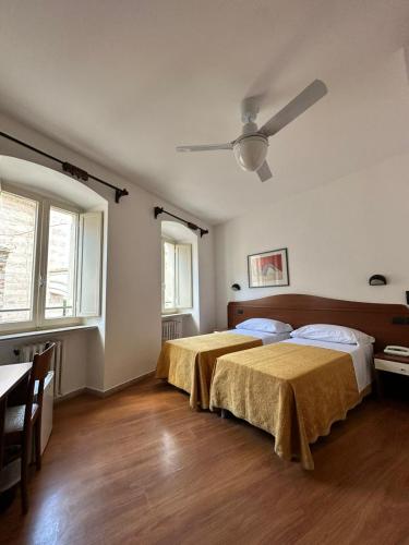 two beds in a bedroom with a ceiling fan at Hotel Roma Assisi in Assisi
