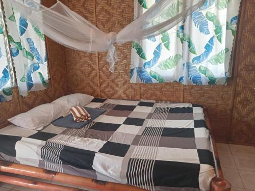 a bedroom with a bed with a checkered bedspread at Enas cottages in Pamilacan IsLand in Baclayon