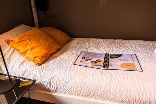 a bed with a book on it with a pillow at Hôtel Palmarès Spa in Spa