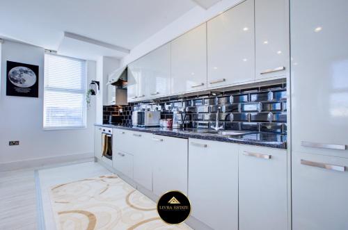 a kitchen with white cabinets and a counter top at Stylish 1 bed Apt By Livra Estate Short Lets & Serviced Accommodation Sutton With Free Parking in Sutton