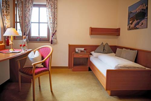 a bedroom with a bed and a desk and a chair at Eggerwirt Kitzbühel, Hotel & Restaurant in Kitzbühel