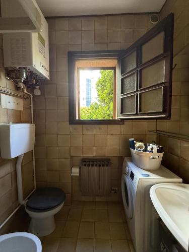 a bathroom with a sink and a toilet and a window at Giardinetto Apartment in Lido di Jesolo