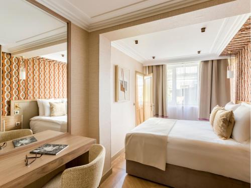 une chambre avec un lit, un bureau et un miroir dans l'établissement Merveil - Signature Suite - Tour Eiffel - Viala IV, à Paris