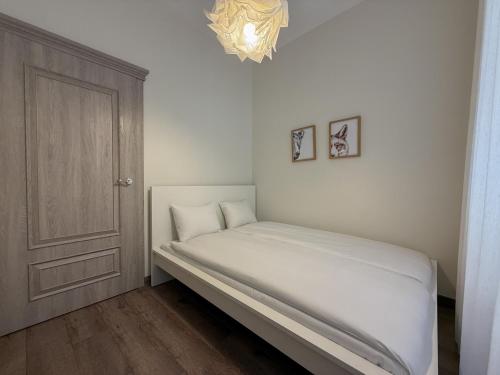 a small bedroom with a bed and a chandelier at S13 Old Town Apartments in Riga