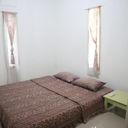 een slaapkamer met een bed en twee ramen bij SHYA House in Batukaras