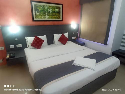 a bedroom with a large white bed with red pillows at StayEasy Tiruvanmiyur (Unit of Prohotel) in Chennai