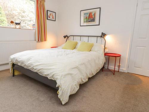 a bedroom with a bed with yellow pillows and a window at 3 Glyn Y Mor in Pwllheli