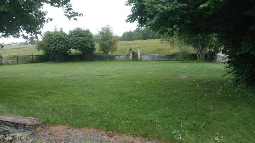 un champ d'herbe verte avec une clôture et des arbres dans l'établissement Corp de ferme, à Villy-Bocage