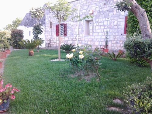 a yard with flowers and a stone house at B&B Tenuta Ranieri in Selva di Fasano