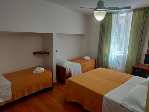 a hotel room with two beds and a window at Hotel Roma Assisi in Assisi