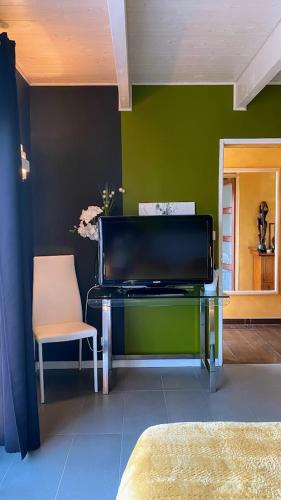 un salon avec une télévision et une chaise dans l'établissement Chambre MELUSINE, à Néant-sur-Yvel