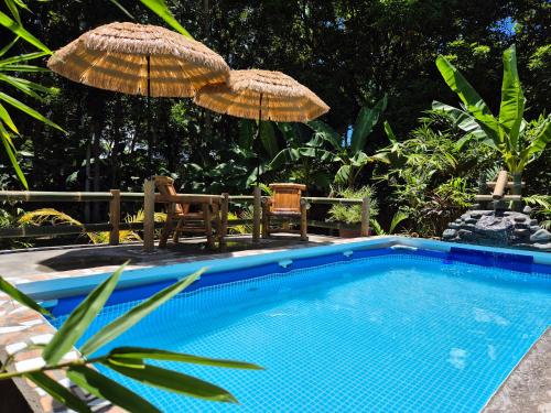 a swimming pool with two chairs and an umbrella at Amazing Ocean View Treehouse & Pool in Puerto Princesa City