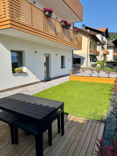 a wooden deck with a black bench and a house at Mountain Lodge in San Lorenzo in Banale