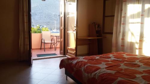 1 dormitorio con 1 cama y puerta a un balcón en Pedi Breeze, en Symi