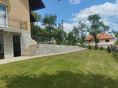 a yard next to a building with a stone wall at VILA ANTONIJE in Šljivovica
