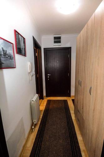 a hallway with a black door and a rug at Centar in Vrnjačka Banja