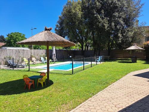 - une table et des chaises sous un parasol à côté de la piscine dans l'établissement les petits chassezac, à Grospierres