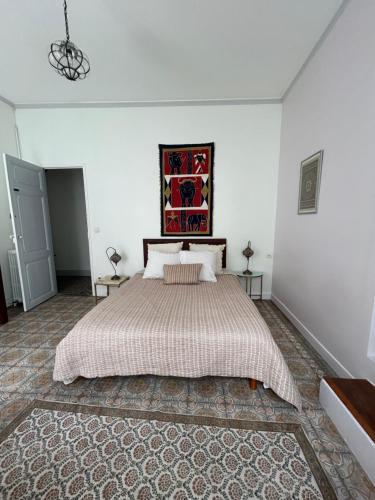 a bedroom with a large bed in a white room at L Oranger in Rivesaltes