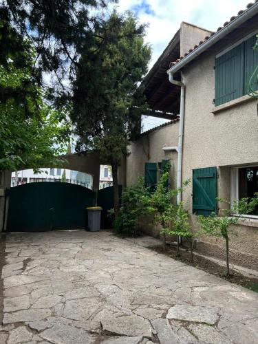a driveway in front of a house with a green fence at Belle chambre en bois chez Antoine in Montpellier