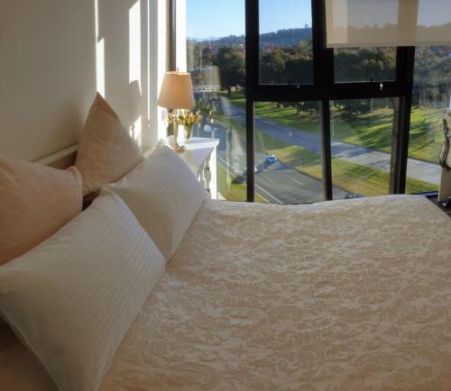 a bedroom with a white bed and a large window at Brand new sunny apartment comfy with views - 2 Bedrooms 2 Baths 2 Parking Gym & Pool in Canberra