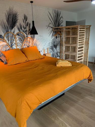 - une chambre dotée d'un grand lit avec des draps orange dans l'établissement Loft sur 2 Étages dans maison individuelle, à Millau