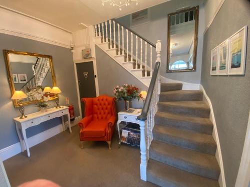 a staircase in a home with a red chair and a mirror at Tyndale B&B Torquay in Torquay