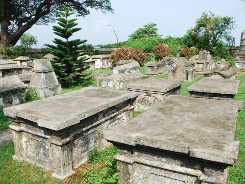 an old cemetery with tombestones in the grass at Sajhome Fortkochi, Kochi, Kerala, inda in Cochin