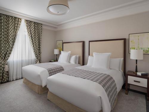 a hotel room with two beds and a window at Raffles London at The OWO in London