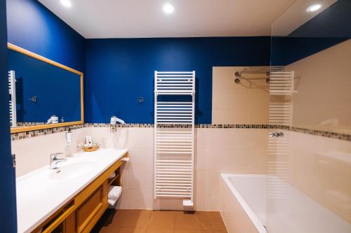 a blue bathroom with a sink and a shower at Les Violettes Hotel & Spa in Jungholtz
