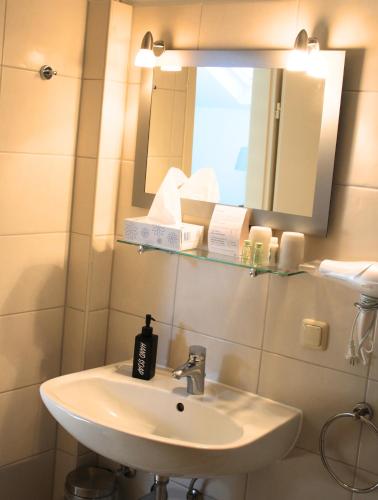 a bathroom with a sink and a mirror at Hotel Adler & Eventlocation GmbH in Itzehoe