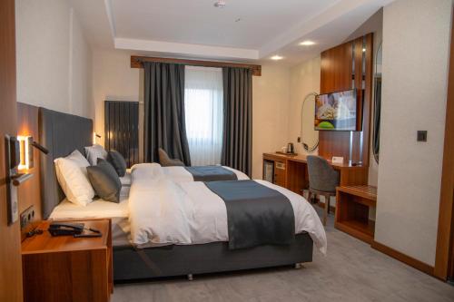 a hotel room with a large bed and a desk at Rest by Dedeman Elbistan in Elbistan