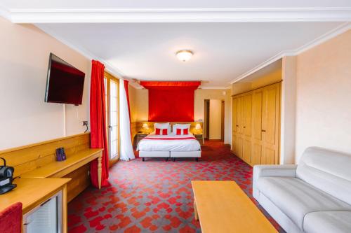 a hotel room with a bed and a couch at Les Violettes Hotel & Spa in Jungholtz