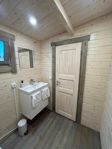 La salle de bains est pourvue d'un lavabo blanc et d'une porte. dans l'établissement Chambre d'hôte le petit chalet, à Sénas