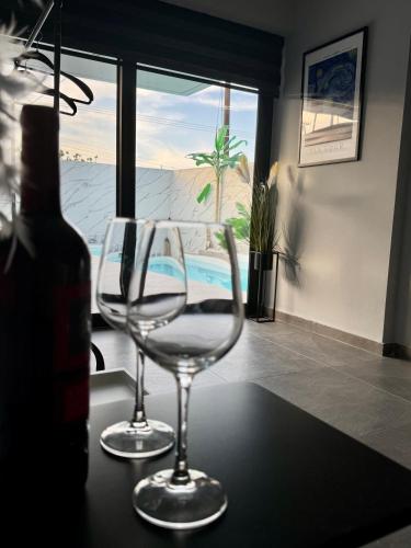 two wine glasses sitting on a table with a bottle of wine at Elite Water House in Patra