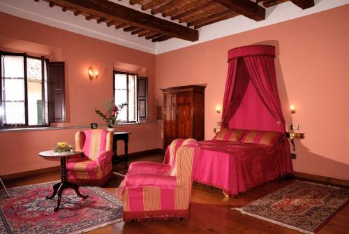 a bedroom with a pink bed and two chairs at Residenza d'Epoca Il Cassero in Lucignano