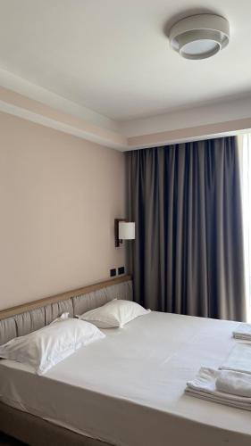 a bedroom with a white bed with a window at Whisky Green Coast Hotel & Apartments in Palasë
