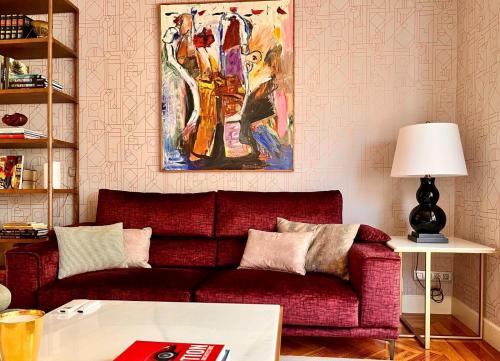 a living room with a red couch and a painting at Habitación en Bilbao-Final EL in Bilbao