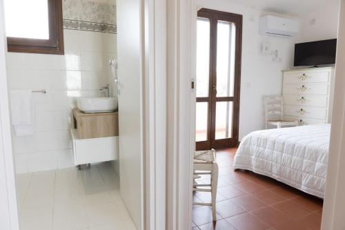 a bedroom with a bed and a bathroom with a sink at Hotel Trinità dei Corsari in Torre Dei Corsari