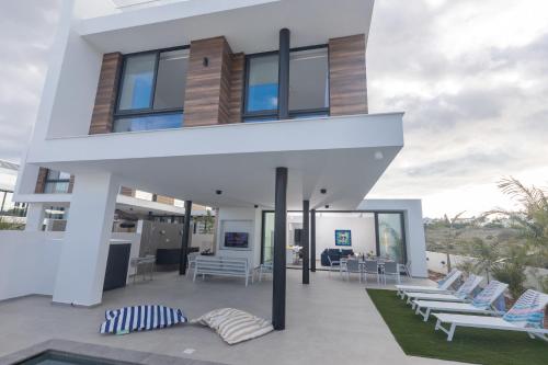 a house on the beach with chairs and a pool at Aqua 4 Bedrooms in Paralimni