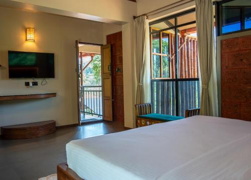 a bedroom with a bed and a tv and a balcony at Villa Katipadu Coorg in Srimangala