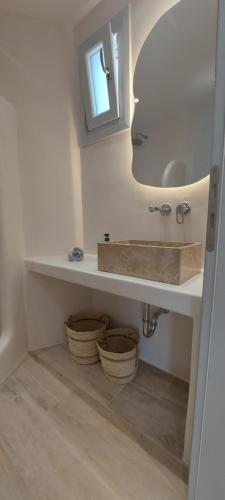 a bathroom with a sink and a mirror and baskets at Apartments Anna Maria in Agia Anna Naxos